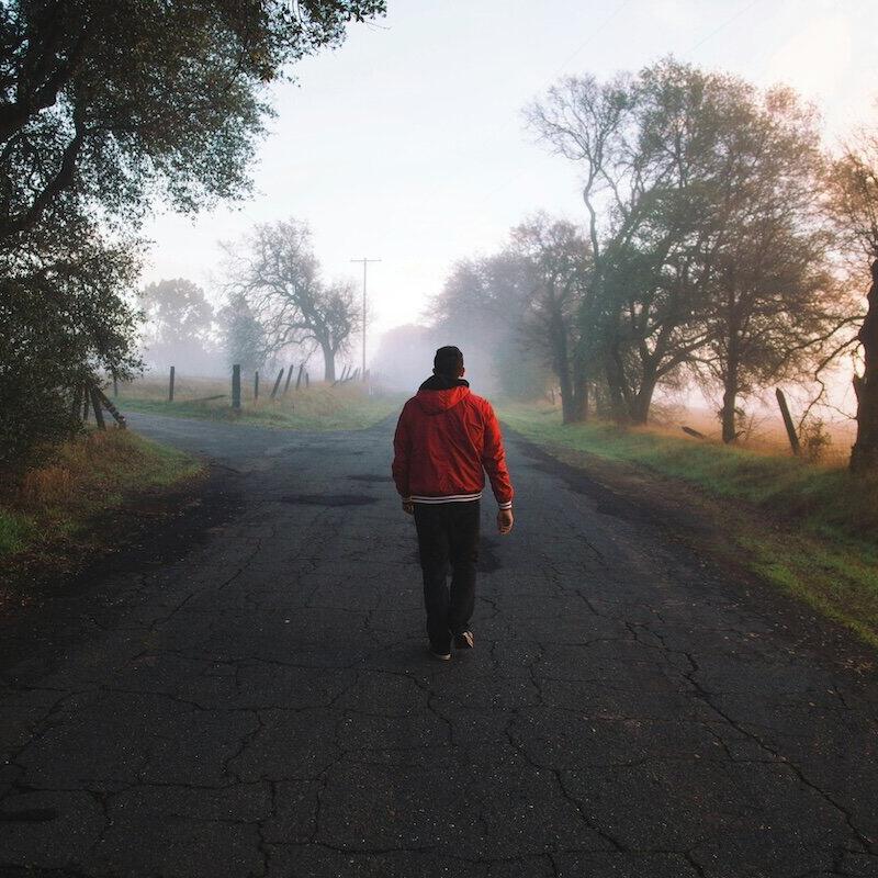 Mann, der tagsüber auf einer ländlichen Straße geht © Jordan McQueen / Unsplash