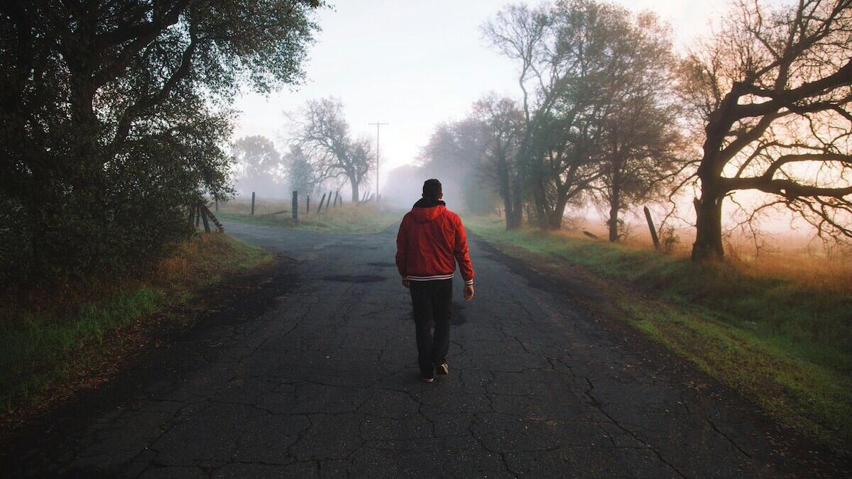 Mann, der tagsüber auf einer ländlichen Straße geht © Jordan McQueen / Unsplash
