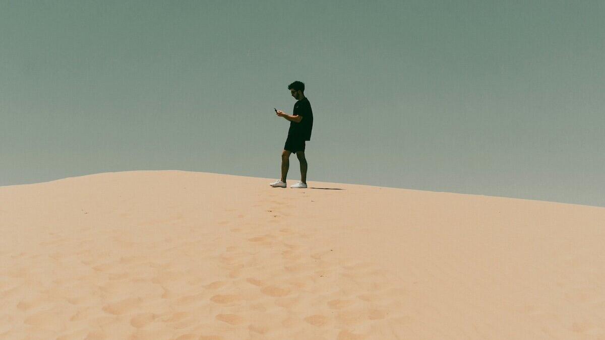 Mann steht auf einer Düne und guckt auf das Smartphone © Bryan Williams / Unsplash Mann steht auf einer Düne und guckt auf das Smartphone © Bryan Williams / Unsplash