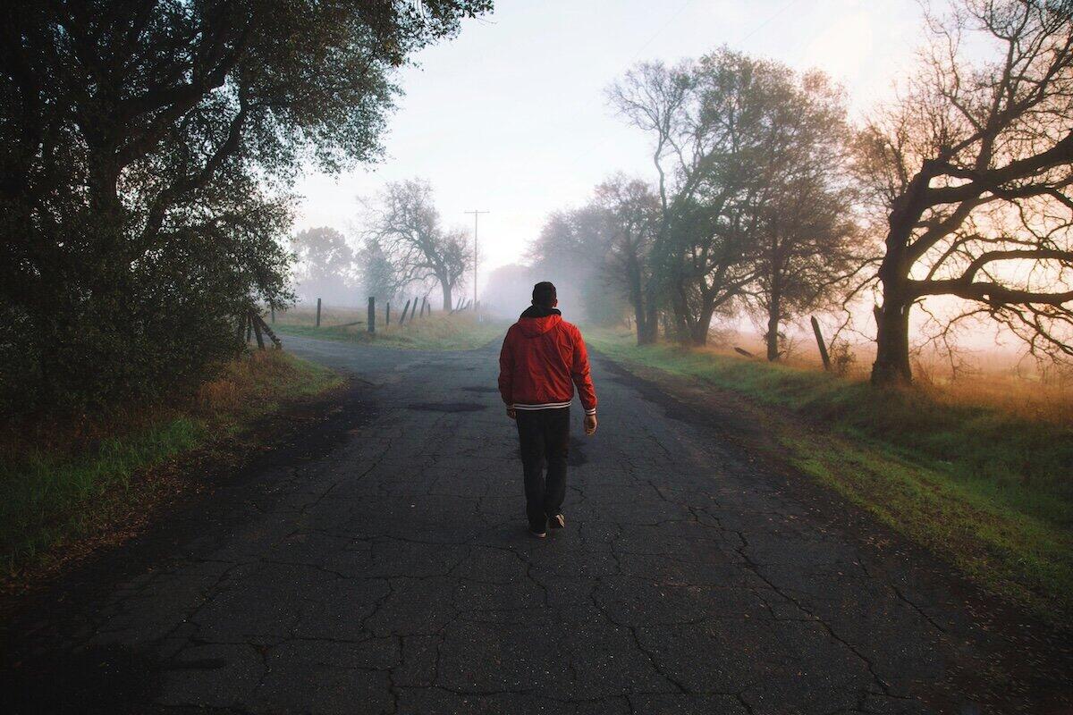 Mann, der tagsüber auf einer ländlichen Straße geht © Jordan McQueen / Unsplash